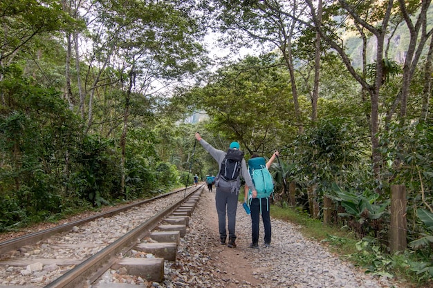 Premium Photo | Backpackers couple walking on railway to machu picchu ...