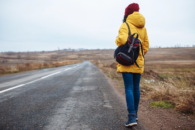 Premium Photo | Backview of a female tourist with a backpack wearing ...