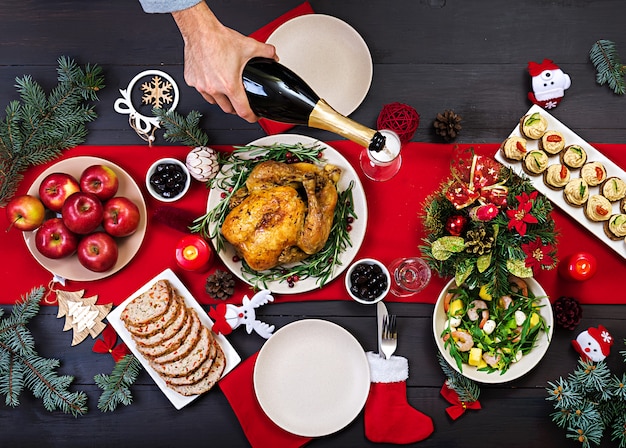 焼き七面鳥。クリスマスディナー。クリスマステーブルには七面鳥が添えられ、明るい見掛け倒しとキャンドルで飾られています。フライドチキン、テーブル。家族との夕食。上面図 無料写真
