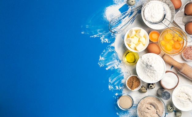 青い色の背景 小麦粉 卵 バター 砂糖 自家製のベーキング用の台所用品の上面図の生地のベーキング材料 テキストのコピースペースと料理のコンセプトバナー プレミアム写真