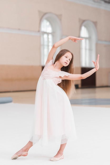 ダンススタジオでポーズを取るピンクのドレスでバレリーナの女の子 無料の写真