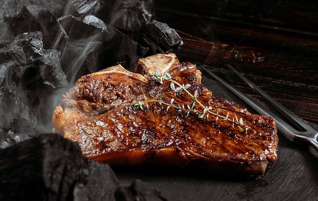 Premium Photo Barbeque Steak On A Black Slate Board With Meat Fork And Grill Coals