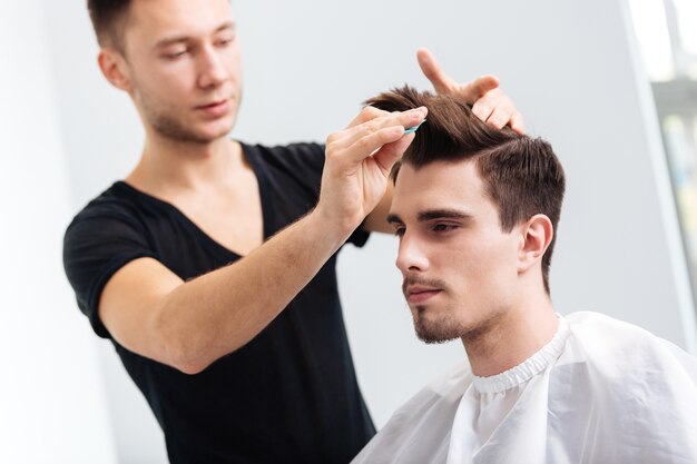 Premium Photo | Barber combing hair to his client in barbershop