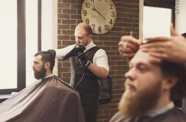 Premium Photo | Barbers work in barbershop with bearded clients. making ...