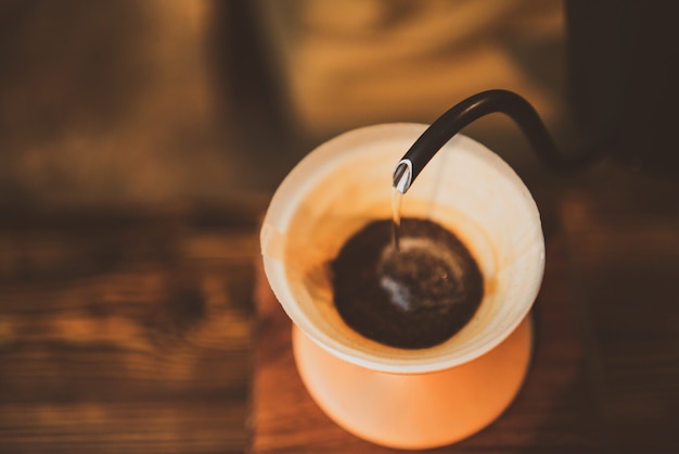 朝にコーヒーフィルターのドリップを醸造するバリスタ 新鮮な黒いエスプレッソの香りの飲み物 カフェのカップでの温かい飲み物 バーショップの背景での茶色のカフェイン プレミアム写真