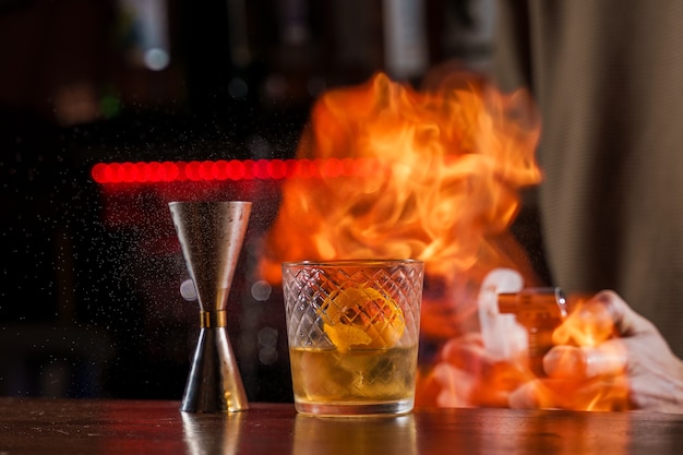 Premium Photo | The bartender makes flame over a cocktail with orange ...