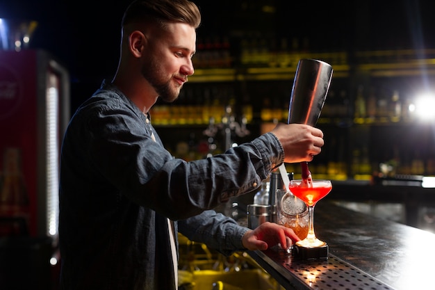 Free Photo | Bartender making a cocktail with a shaker