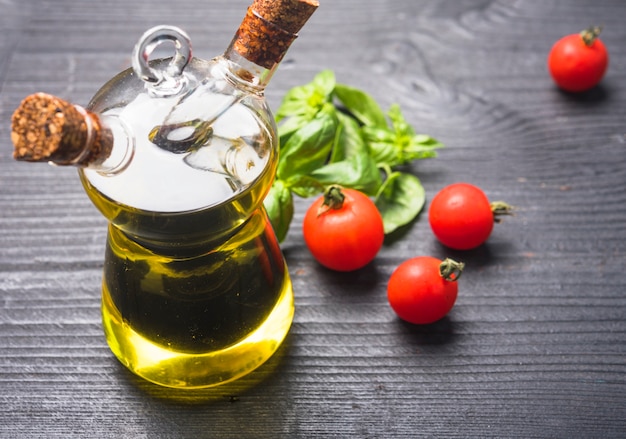 Free Photo | Basil leaves; tomatoes and bottle of olive oil with cork