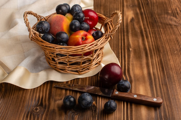 Basket with frutis blackthorns plums and peaches on wood Free Photo