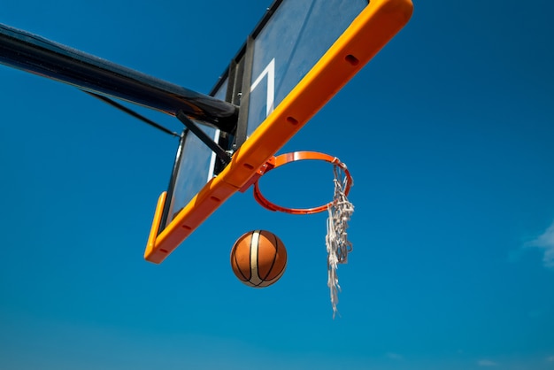 Premium Photo | Basketball ball falling through old net blue sky on ...