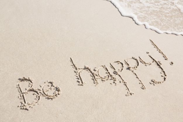 Be happy written on sand - Freepik