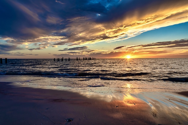 Beach Surrounded By The Sea With Vertical Wooden Planks In It During The Sunset In The Evening Free Picture On Freepik