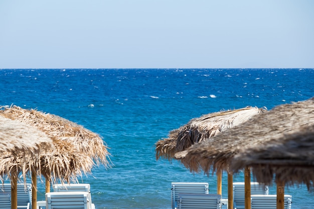 Beach with umbrellas and deck chairs by the sea in santorini Premium Photo