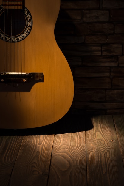 Premium Photo | A beam of light illuminates an acoustic guitar standing ...