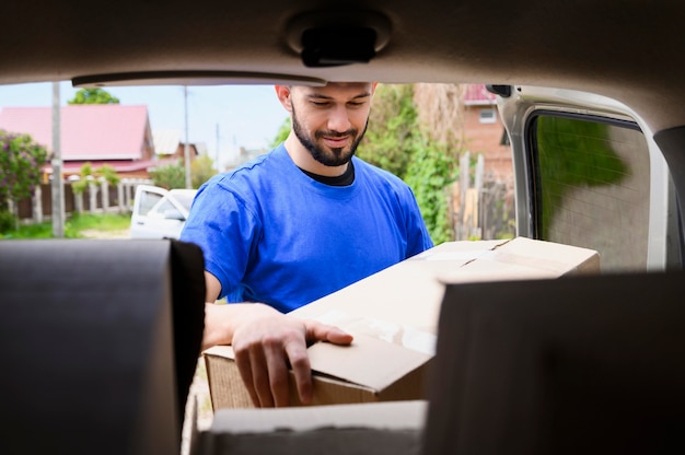 Bearded man taking delivery boxes out of van Free Photo