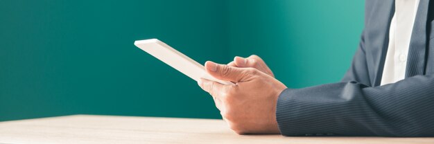 Bearded smiling asian man using tablet for video conversation while relaxing on sofa in modern office.concept of young business people working at home. panoramic banner. Free Photo