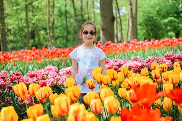 チューリップ畑にチューリップの花の臭いがする美しいオランダの女の子 オランダのチューリップの花畑の子 キューケンホフのチューリップ畑と魔法のオランダの風景の中の子供 旅行と春のコンセプト プレミアム写真