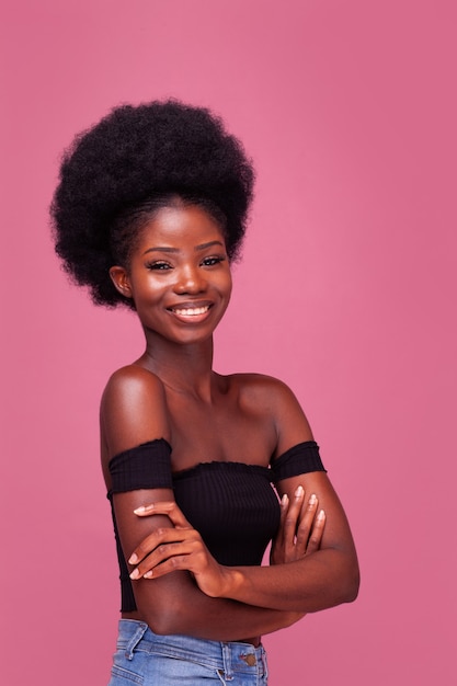 腕を組んで笑顔で立っているゴージャスなアフロ髪型の美しいアフリカ系アメリカ人の女の子 プレミアム写真