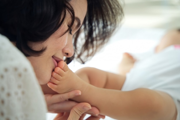子供が眠っている間に目を閉じて彼女の赤ちゃんの足にキス美しいアジアの母親 プレミアム写真