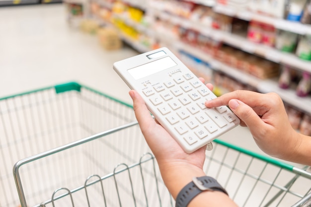 A beautiful asian woman holding a calculator to calculate the cost and price reduction Premium Photo