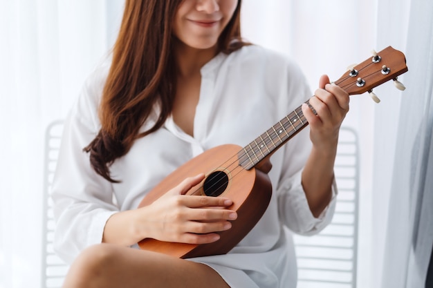 Premium Photo | A beautiful asian woman sitting and playing ukulele in ...