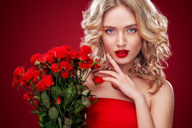 Beautiful blonde woman holding bouquet of red roses Premium Photo