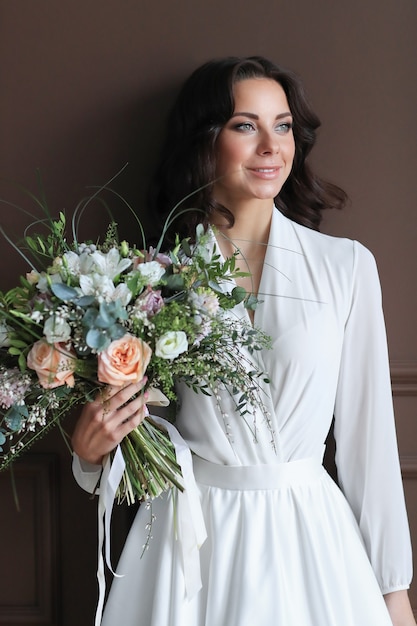 花の花束と白いローブの美しい花嫁の女性 無料の写真