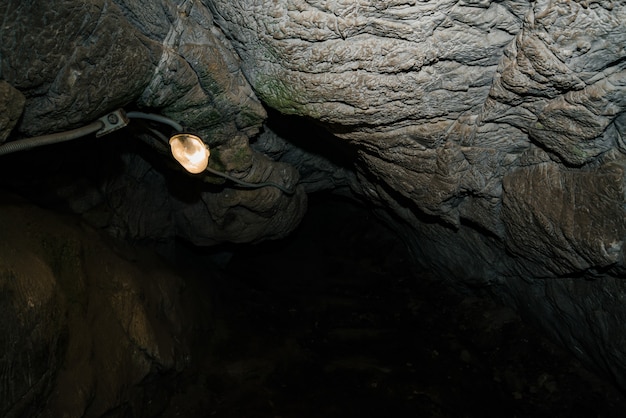 プレミアム写真 美しい洞窟 暗いダンジョンの中からの眺め 洞窟のテクスチャ壁 洞窟の中の湿気 遠足用の洞窟内の照明