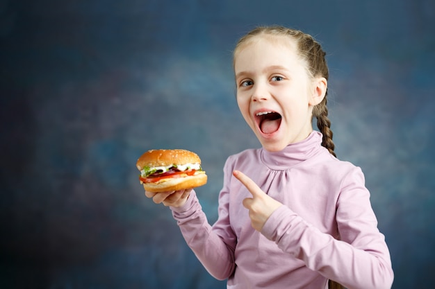 美しいかわいい白人の女の子は彼女の手でハンバーガーを示しています プレミアム写真