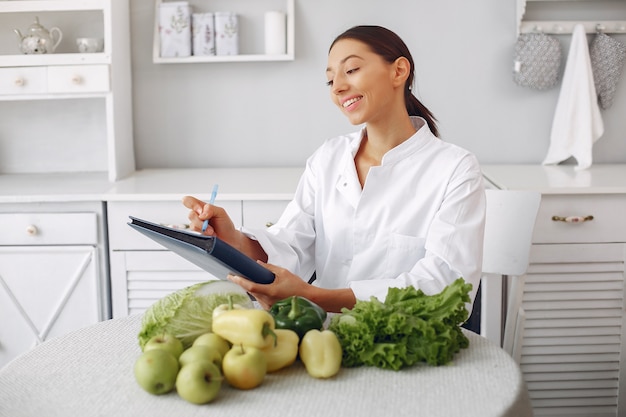 Beautiful doctor in a kitchen with vegetables Free Photo