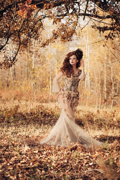 Beautiful elegant woman standing in the autumn forest in chiffon dress ...