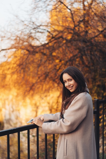 Beautiful elegant woman standing in a park in autumn Free Photo