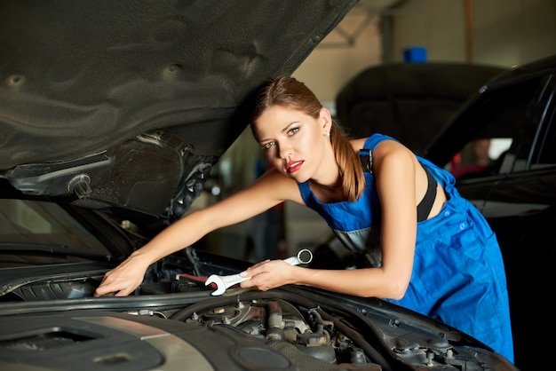 Premium Photo | Beautiful female mechanic repairs the car with a wrench.