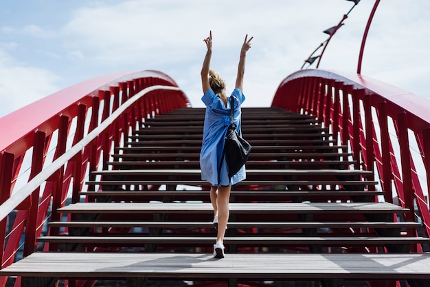 Beautiful girl in a blue dress posing on the bridge Free Photo