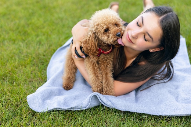 Beautiful girl and her pet little golden poodle dog strolling in public park outdoors Dogs that don't shed