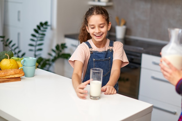 Premium Photo | Beautiful happy little girl with a glass of milk in the ...