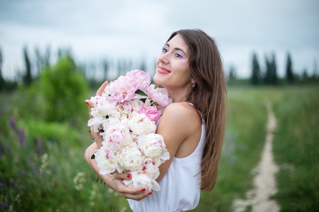 牡丹と美しい幸せな笑顔の女性花の花束を持つ女の子 プレミアム写真