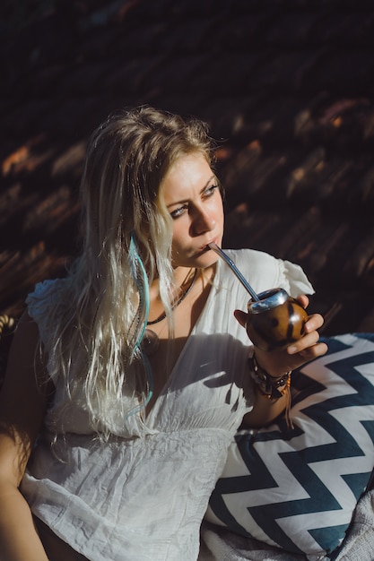 tisane anti fatigue Belle fille hippie indienne aux longs cheveux blonds sur le toit, boire du thé maté.