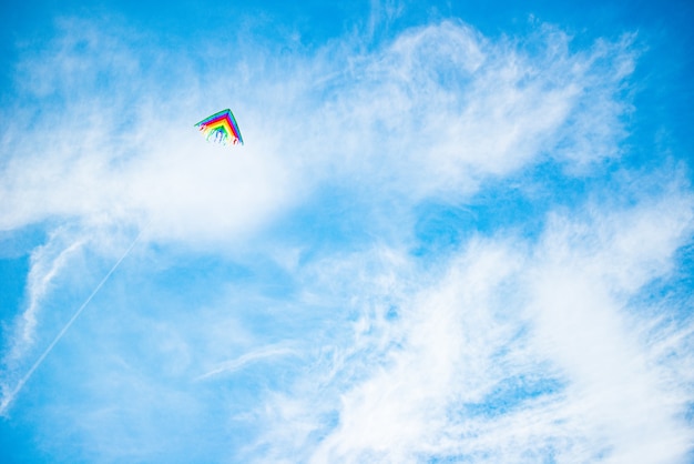虹の鮮やかな色の美しい凧が晴れた青い空を飛んでいます プレミアム写真