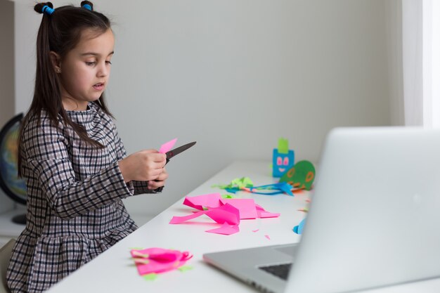 Premium Photo | Beautiful little girl cutting paper with ...