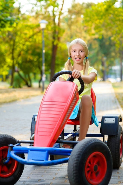 Premium Photo | Beautiful little girl riding toy car in summer city park