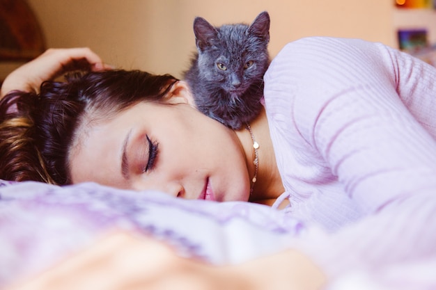 彼女の猫と一緒に自宅で昼寝をする美しい孤独な女性 疲れた女性と寝ているふわふわ子猫 プレミアム写真