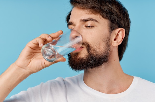 Premium Photo Beautiful Man Drinking Water From A Glass On A Blue Background Close Up Portrait 5197