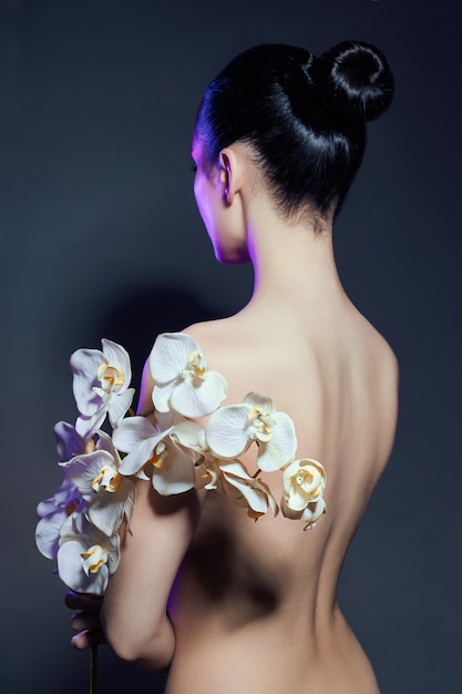 Beautiful nude woman with a branch of white orchid Premium Photo