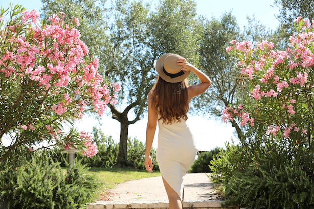 イタリアのガルダ湖のシルミオーネの花の間の庭に入る美しいセクシーなファッションの女性 プレミアム写真