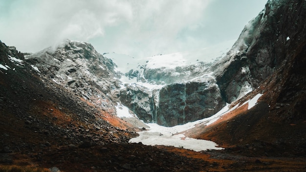 Free Photo Beautiful Shot Of Snowy And Rocky Mountains Covered In Mist On A Sunny Day