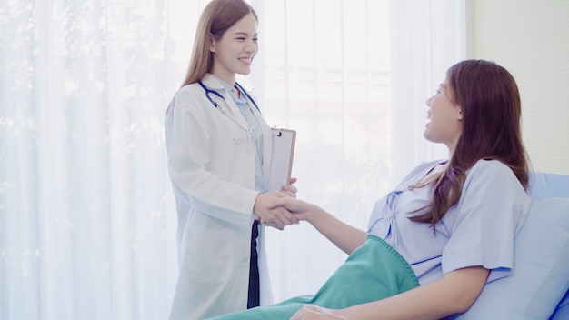 Beautiful smart asian doctor and patient discussing and explaining something with clipboard Free Photo