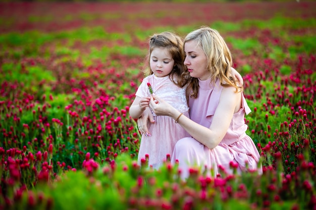 Premium Photo Beautiful Smiling Child Girl With Young Mother In Family Look In Field Of Clover Flowers In Sunset Time