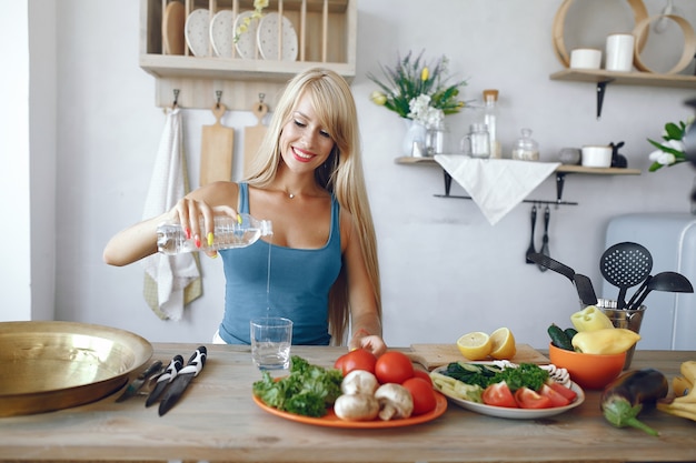 Beautiful and sporty girl in a kitchen with a vegetables Free Photo