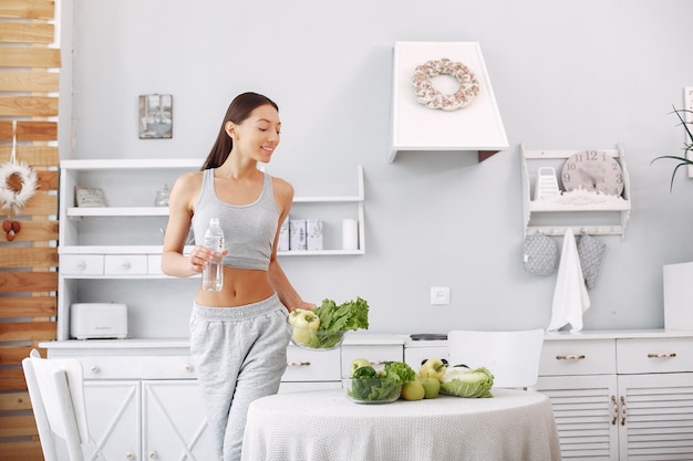 Beautiful and sporty woman in a kitchen with vegetables Free Photo